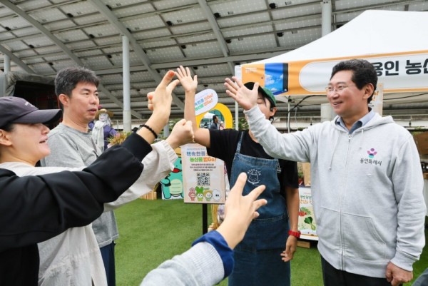 7. 이상일 용인특례시장이 18일 시청 광장에서 열린 책 속 한 줄 쓰Go, 농산물 받Go 행사에서 시민들과 인사를 나누고 있다..jpg